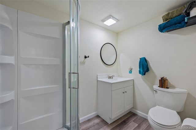 bathroom featuring vanity, wood-type flooring, a shower with door, and toilet