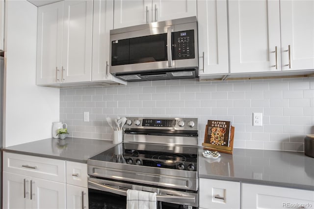 kitchen featuring backsplash, white cabinets, stainless steel appliances, and dark countertops