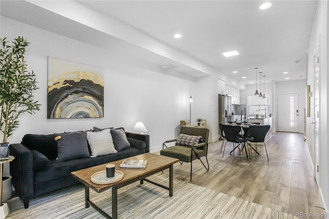 living room featuring recessed lighting, light wood-type flooring, and baseboards