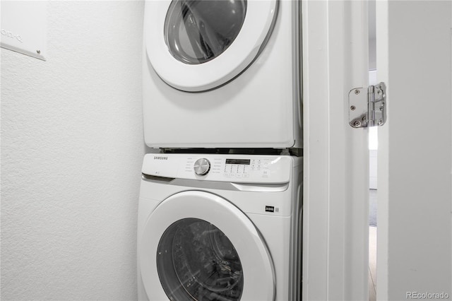 laundry room featuring stacked washer / dryer, laundry area, and a textured wall