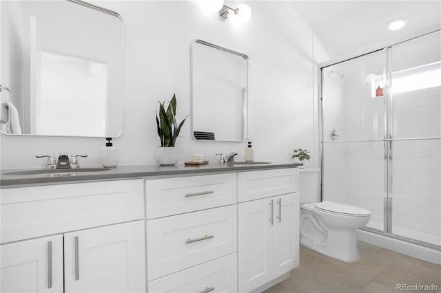 bathroom with double vanity, a stall shower, toilet, and a sink