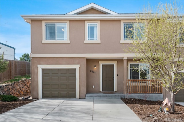 view of front of house featuring a garage, concrete driveway, stucco siding, and fence