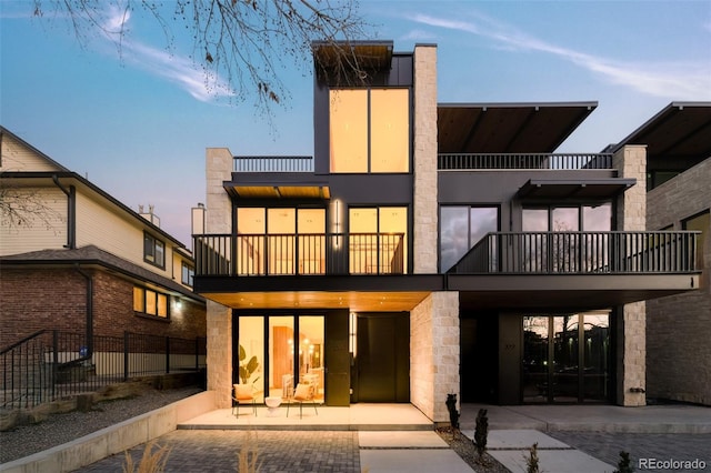 back house at dusk featuring a balcony