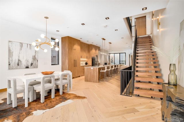 dining space featuring sink, wood walls, light parquet flooring, and a notable chandelier