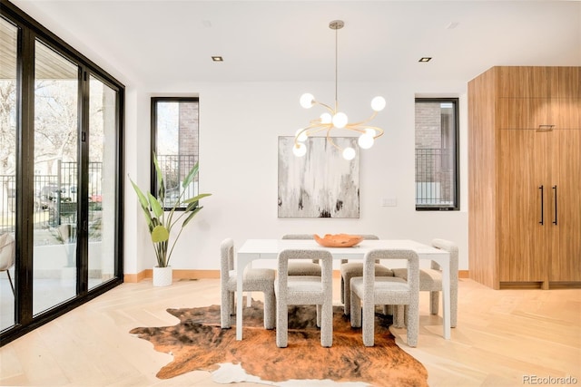 dining area featuring light hardwood / wood-style floors, a chandelier, and a wall of windows