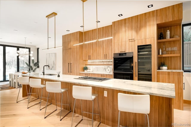 kitchen with stainless steel gas stovetop, decorative light fixtures, light stone countertops, black double oven, and a breakfast bar area