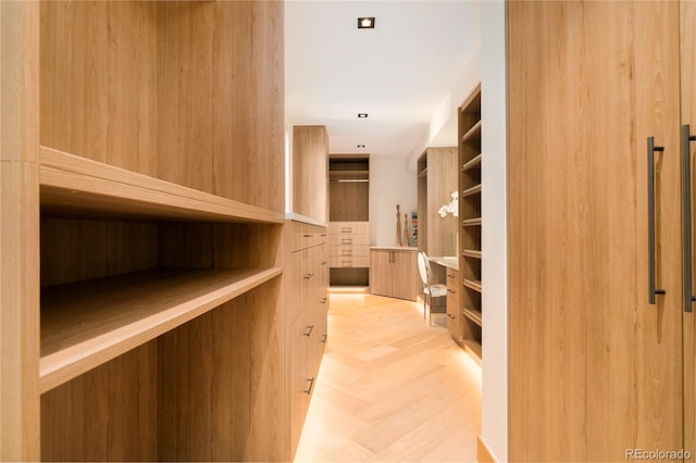 walk in closet with light parquet floors