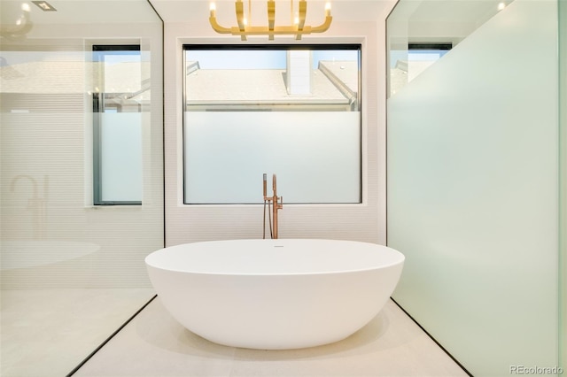 bathroom featuring a healthy amount of sunlight, a bath, tile patterned flooring, and a notable chandelier