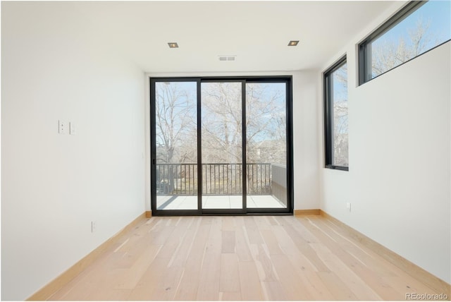 unfurnished room with floor to ceiling windows, plenty of natural light, and light wood-type flooring