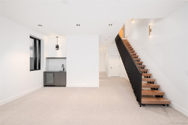 unfurnished living room featuring sink and light carpet