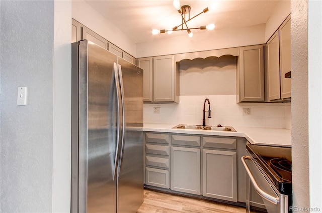 kitchen featuring gray cabinets, tasteful backsplash, sink, light hardwood / wood-style flooring, and stainless steel appliances