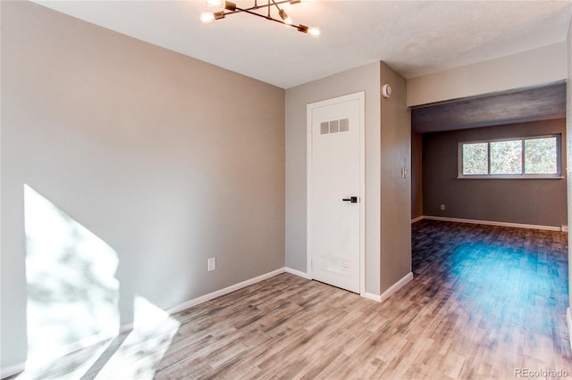 spare room featuring a chandelier and hardwood / wood-style floors