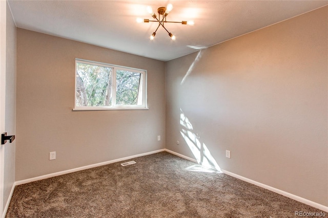 carpeted empty room with a chandelier