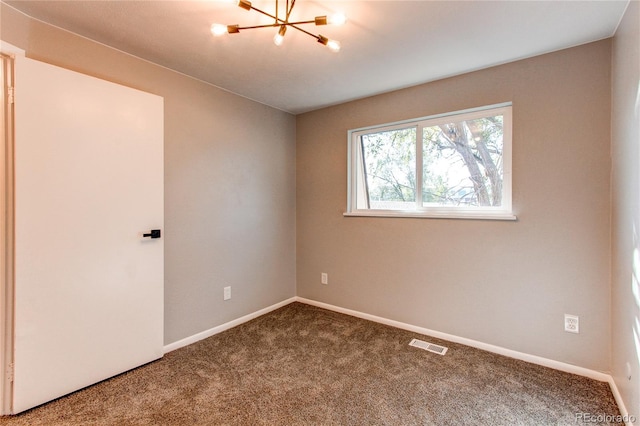 empty room with a notable chandelier and carpet floors