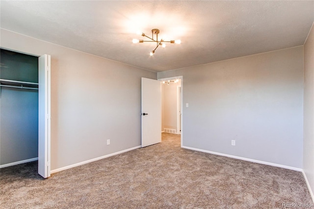 unfurnished bedroom with carpet floors, a chandelier, and a closet