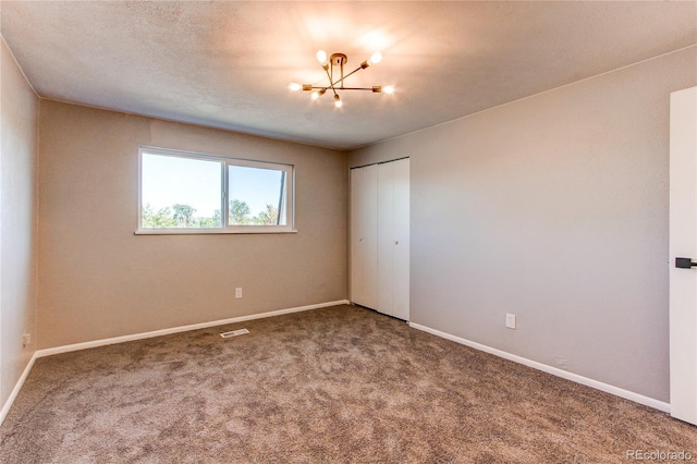 unfurnished bedroom featuring a notable chandelier, a closet, and carpet