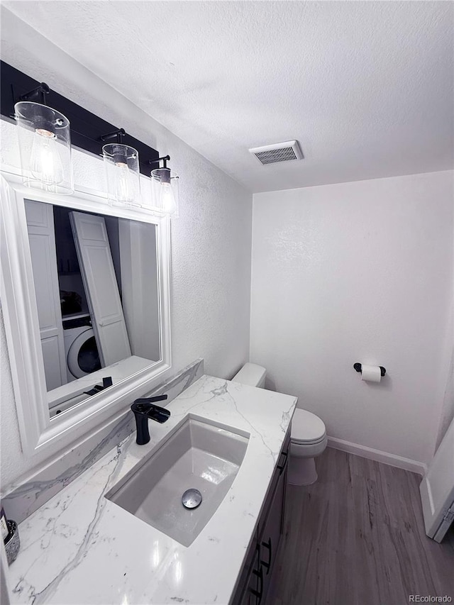 bathroom with vanity, toilet, and a textured ceiling