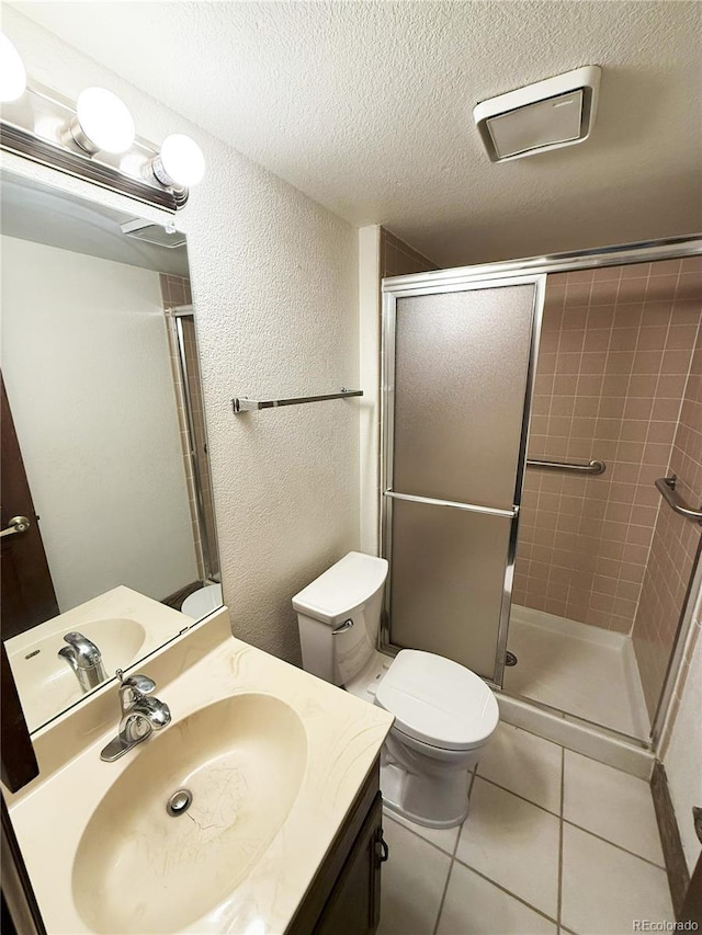 bathroom with tile patterned flooring, vanity, toilet, and a shower with door