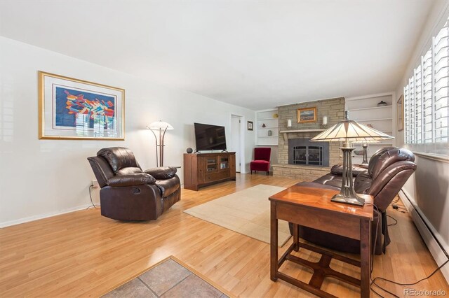1040 Zang St, Golden, CO 80401 - living area with wood finished floors, built in features, a stone fireplace, baseboards, and a baseboard radiator