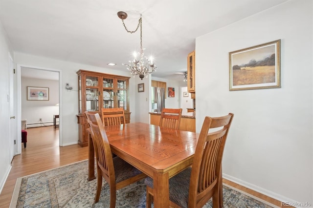 1040 Zang St, Golden, CO 80401 - dining area with baseboard heating, a chandelier, light wood finished floors, and baseboards