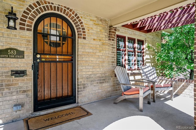 entrance to property featuring covered porch and brick siding