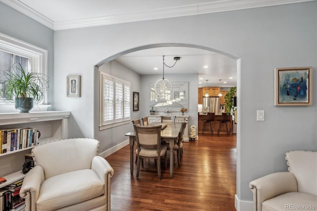 dining area featuring baseboards, arched walkways, dark wood-type flooring, crown molding, and a chandelier