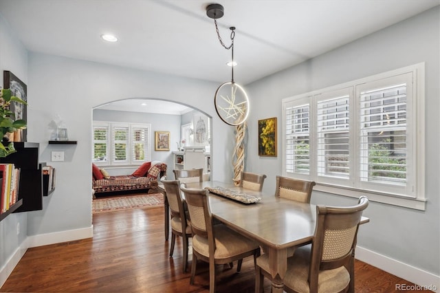 dining area featuring baseboards, arched walkways, and wood finished floors