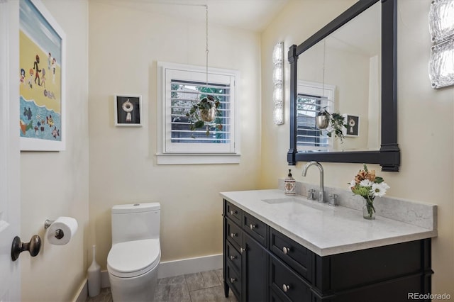 bathroom with baseboards, vanity, and toilet