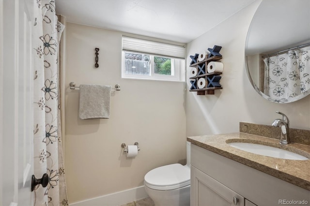 bathroom with baseboards, vanity, and toilet