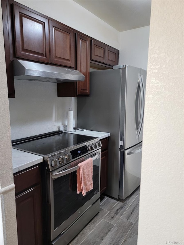 384 S Ironton St Unit 407, Aurora, CO 80012 - kitchen with appliances with stainless steel finishes, under cabinet range hood, wood finish floors, and dark brown cabinetry