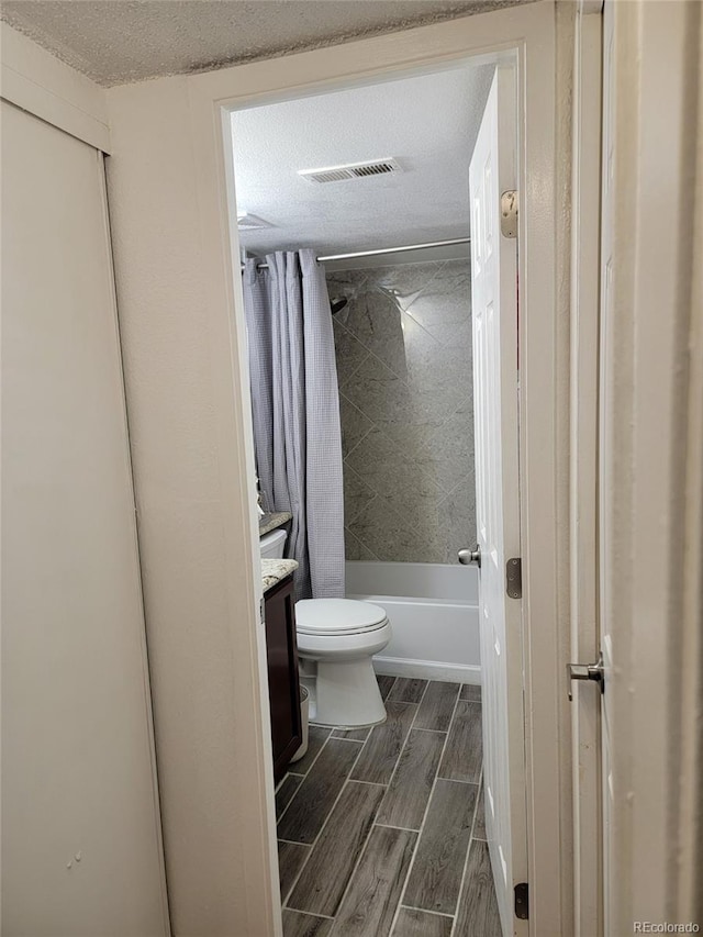 384 S Ironton St Unit 407, Aurora, CO 80012 - bathroom with toilet, vanity, shower / bathtub combination with curtain, wood tiled floors, and a textured ceiling