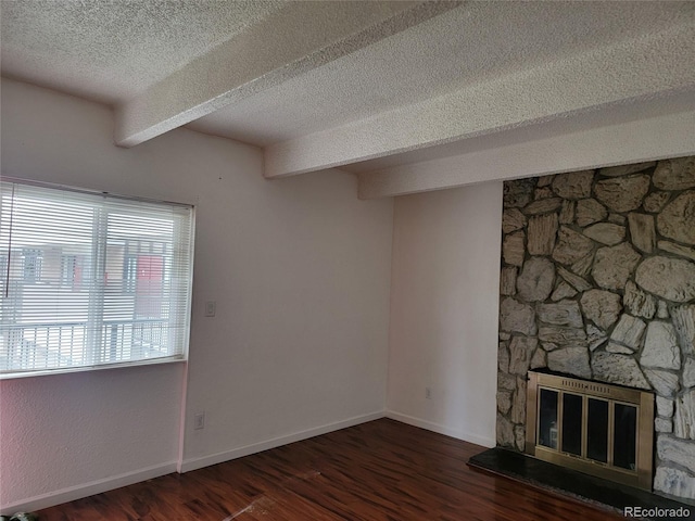 384 S Ironton St Unit 407, Aurora, CO 80012 - unfurnished living room with a textured ceiling, wood finished floors, a fireplace, beamed ceiling, and baseboards