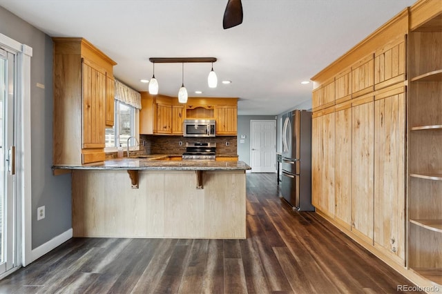 kitchen with kitchen peninsula, a breakfast bar, stainless steel appliances, dark wood-type flooring, and pendant lighting