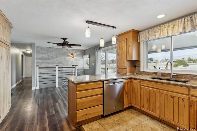 kitchen with ceiling fan, sink, hanging light fixtures, stainless steel dishwasher, and kitchen peninsula