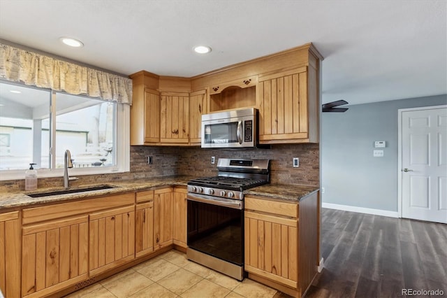 kitchen with sink, ceiling fan, decorative backsplash, dark stone countertops, and appliances with stainless steel finishes