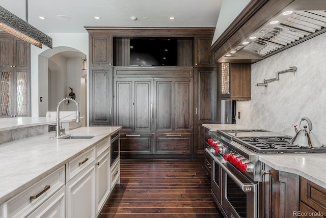 1820 Mallard Dr, Broomfield, CO 80020 - kitchen featuring double oven range, a sink, wall chimney range hood, arched walkways, and dark wood-style floors