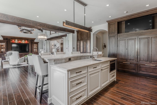 1820 Mallard Dr, Broomfield, CO 80020 - kitchen with a sink, arched walkways, dark wood-style flooring, open floor plan, and a kitchen breakfast bar