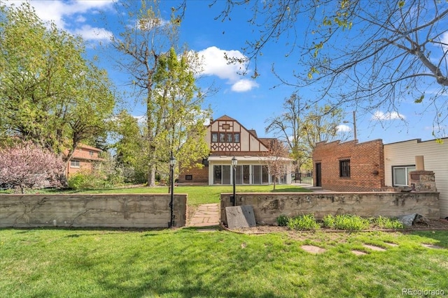 back of house with a lawn and brick siding