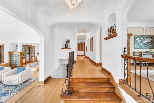 interior space featuring crown molding, arched walkways, and wood finished floors