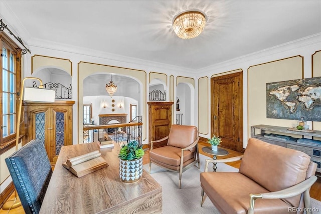 living area with crown molding, arched walkways, a chandelier, baseboards, and wood finished floors