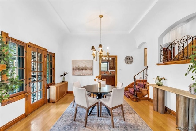 dining room with arched walkways, stairs, wood finished floors, and a notable chandelier