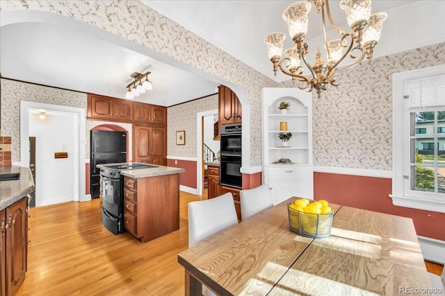 kitchen featuring arched walkways, light wood-style flooring, black appliances, and wallpapered walls