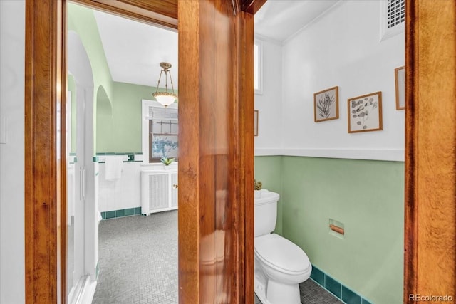 bathroom with a healthy amount of sunlight, radiator, toilet, and visible vents