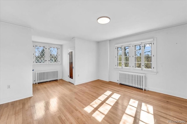 spare room featuring baseboards, radiator heating unit, and wood finished floors