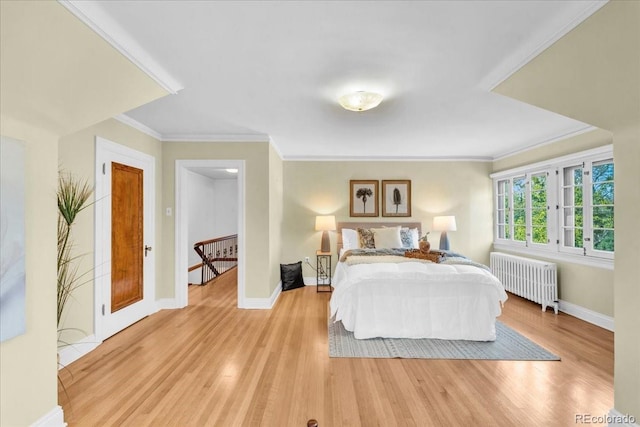bedroom with baseboards, radiator heating unit, and light wood-style flooring
