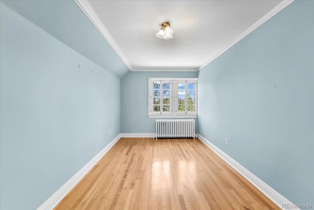 additional living space with baseboards, radiator, and light wood-style floors