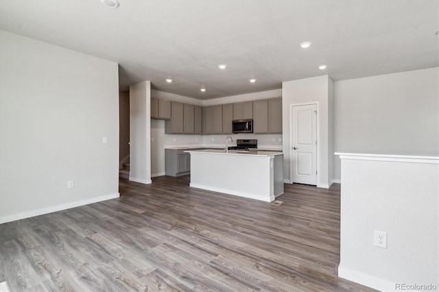 14131 Deertrack Ln, Parker, CO 80134 - kitchen featuring stainless steel microwave, recessed lighting, wood finished floors, a center island with sink, and gray cabinetry