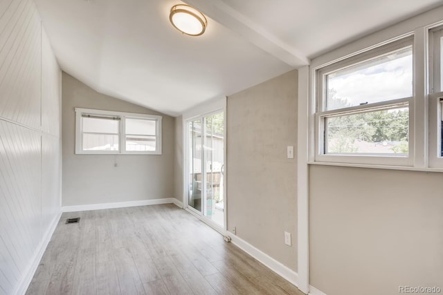 empty room featuring light wood-type flooring and vaulted ceiling