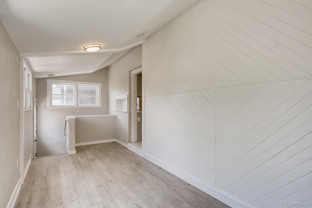 unfurnished room featuring light wood-type flooring and vaulted ceiling