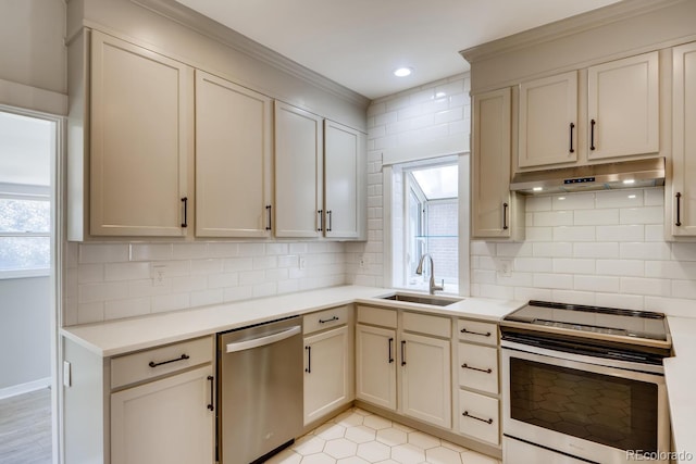 kitchen with backsplash, cream cabinetry, sink, and appliances with stainless steel finishes